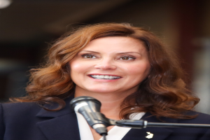 Michele Bachmann, eine Frau in Anzug und Krawatte, spricht in ein Mikrofon mit unscharfem Hintergrund.