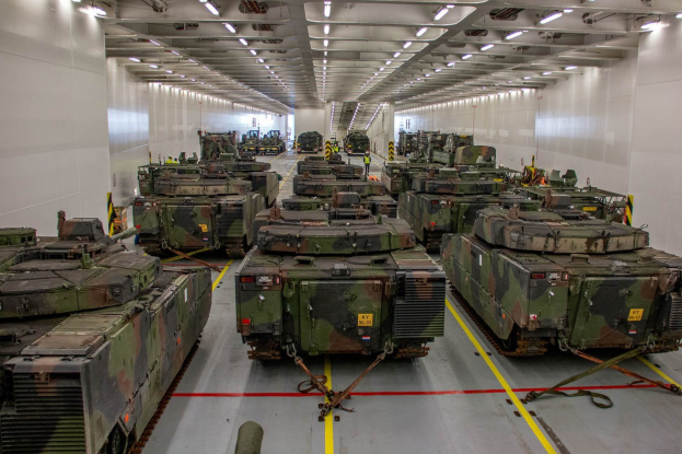 Eine gro├če Militargelandehalle mit Reihen von Militartanks, Wanden auf beiden Seiten und Deckenbeleuchtung.