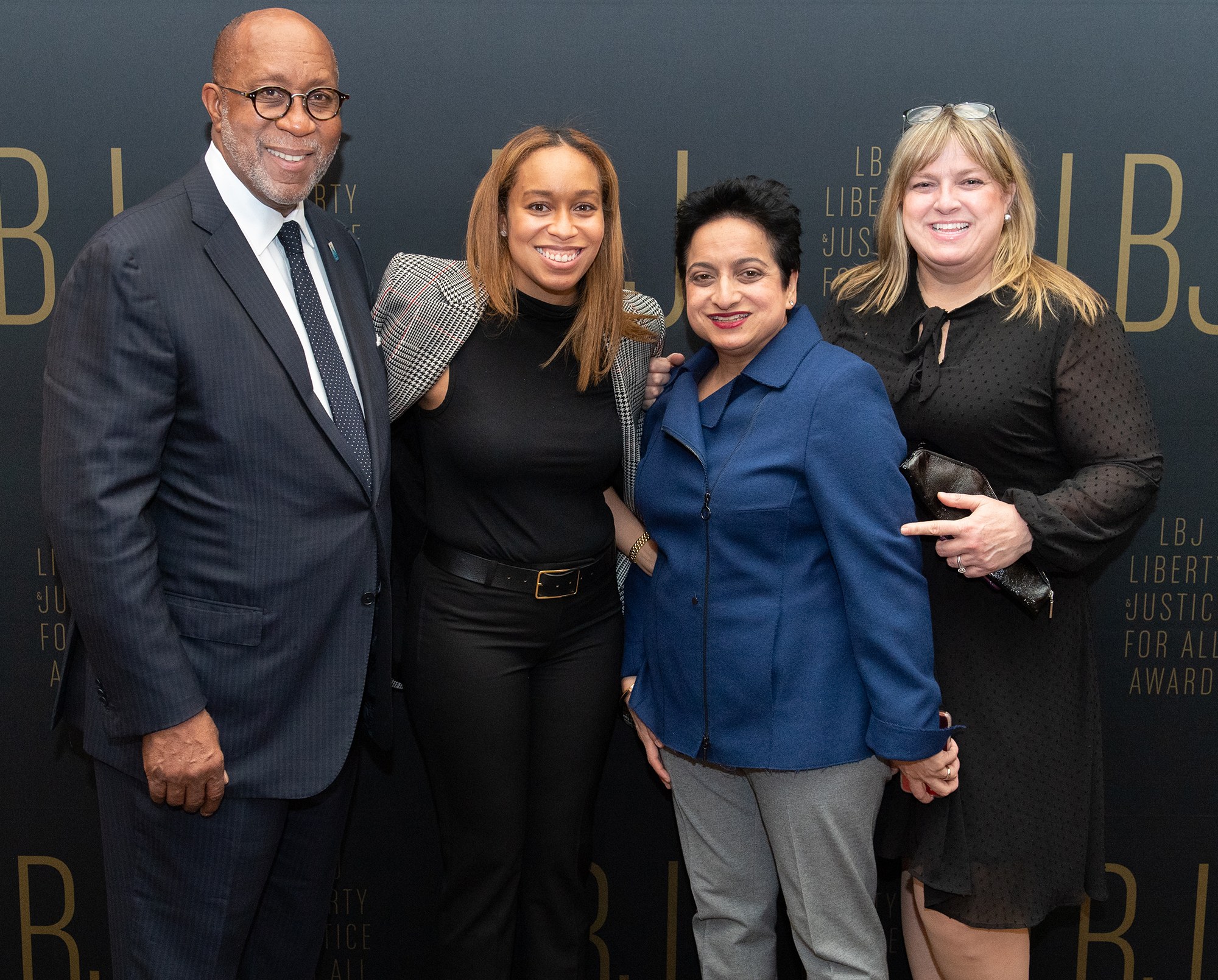Vier Personen posieren auf einem roten Teppich mit einem "Liberty Justice for All Awards"-Hintergrund.