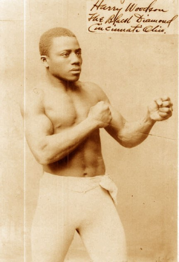 Ein Schwarz-Weiß-Foto eines Mannes im Boxring mit Handschuhen und Shorts, der entschlossen dastand.