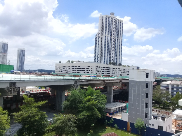 Luftaufnahme einer Stadt mit Gebäuden, Bäumen, Gras, Fahrzeugen, einer Brücke, Polen und Wolken, die eine Baustelle für einen neuen Wohnkomplex zeigt.