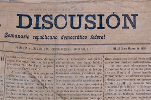 Eine vergilbte, leicht zerknitterte Zeitung mit dem Wort "Diskussion" in schwarzer Schrift, die die Schlagzeile "Semanario Repúblicano Democrático Federal" trägt.