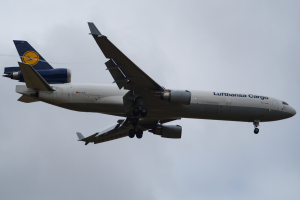 Ein Lufthansa Cargo Boeing 777-300ER-Flugzeug im Flug, mit sichtbarem Text an der Seite, vor einem Hintergrund aus weißen, flauschigen Wolken.