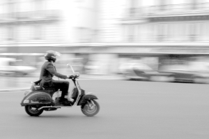Eine Person, die einen Roller auf der Straße fährt.