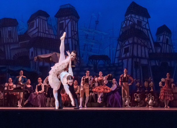 Zwei Balletttänzerinnen, die auf der Bühne vor einem Publikum tanzen, mit einem gemalten Hintergrund aus *Romeo und Julia* im Hintergrund.