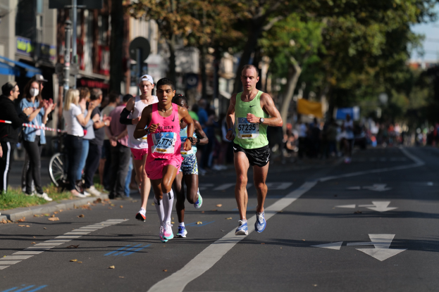 Eine Gruppe von Menschen, die bei einem Marathon auf einer Stadtstraße laufen