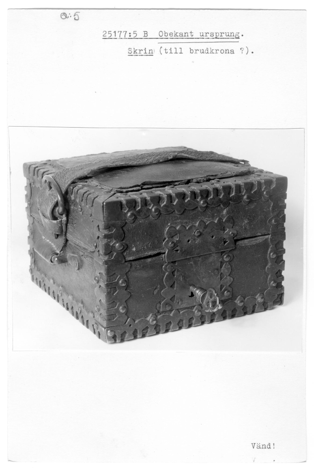 Ein kleines hölzernes Kästchen mit einem Schloss, das auf einer weißen Oberfläche steht und an eine Schatzkiste erinnert.