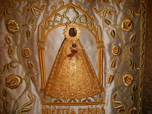 Golddurchwirkter Chorsatz mit einer friedlichen Frau in einem hochgeschlossenen, langärmligen Kleid mit einem Dutt, umgeben von detaillierten Texten und prächtigen goldenen Designs.
