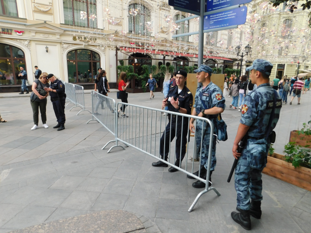 Polizeibeamte in Uniform stehen hinter Absperrungen und blicken auf eine Menge, von denen einige Mützen tragen und Waffen halten, mit Gebäuden und Grünflächen im Hintergrund während einer Anti-Terror-Operation in Wien, Österreich.