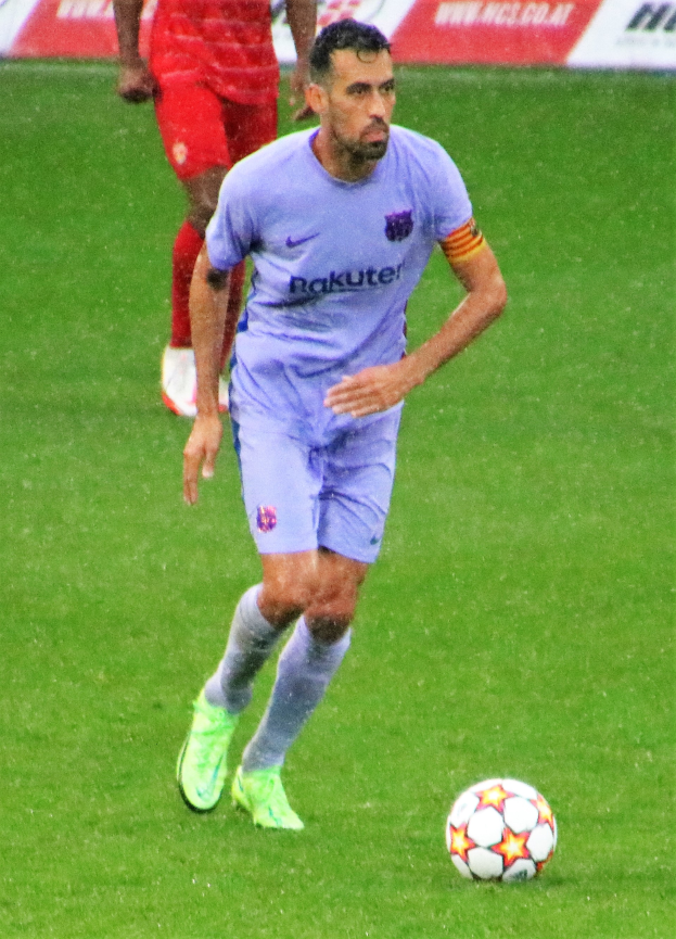 Ein Fußballer in Sportkleidung und -schuhen ist im Einsatz auf dem Feld mit einem Textschild im Hintergrund.