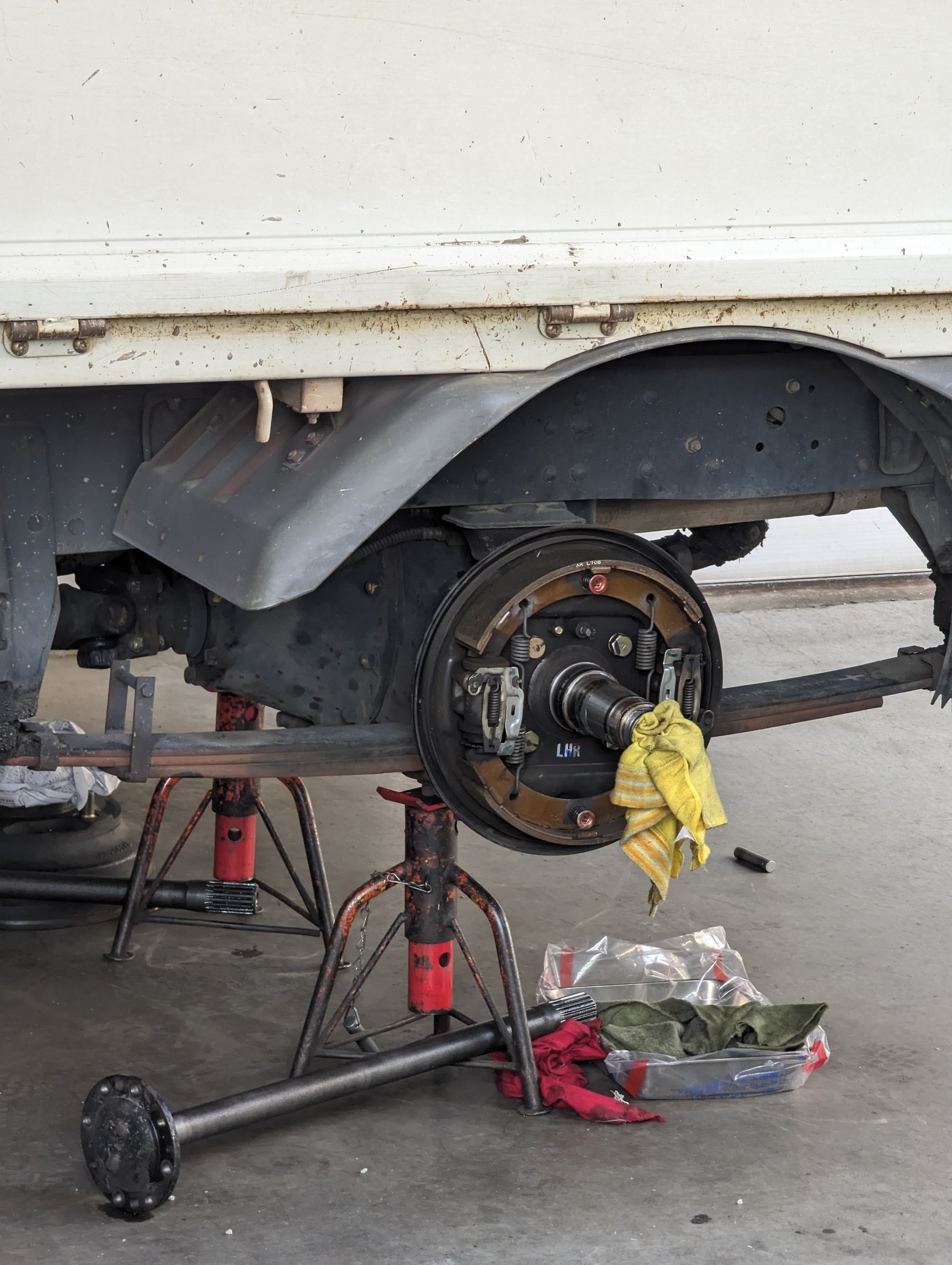 Ein gelber, tuchbedeckter Lkw in einer Garage mit Werkzeugen und Gegenst\c3\a4nden auf dem Boden davor.