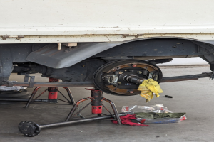 Ein gelber, tuchbedeckter Lkw in einer Garage mit Werkzeugen und Gegenst\c3\a4nden auf dem Boden davor.