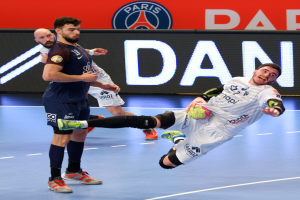 Eine Gruppe von Männern, die auf einem Platz Handball spielen, einer mit einem Ball, mit einem Paris Saint-Germain-Futsal-Team-Schild im Hintergrund.